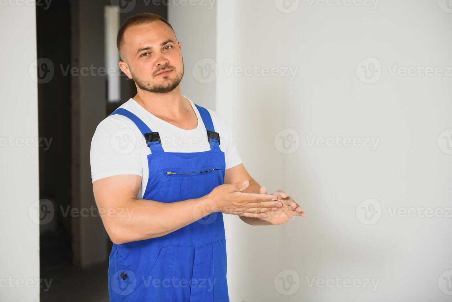 Portrait of young handyman standing on white background with copy space. Repairman wearing workwear uniform. photo