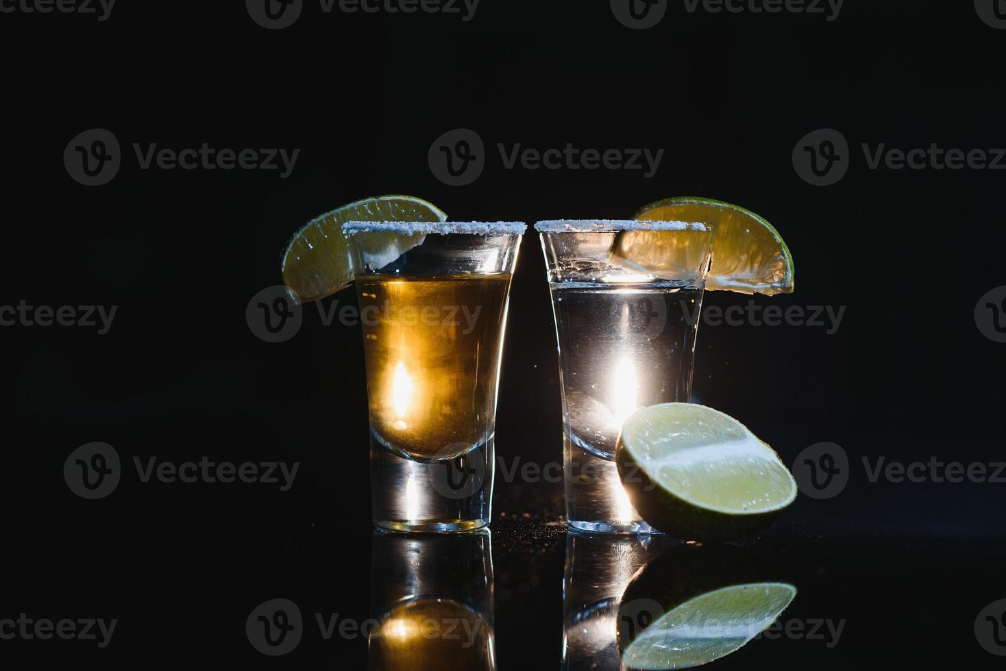 Tasty alcohol drink cocktail tequila with lime and salt on vibrant dark background. Closeup. photo