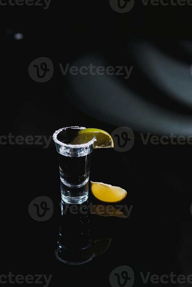 Tasty alcohol drink cocktail tequila with lime and salt on vibrant dark background. Closeup. photo