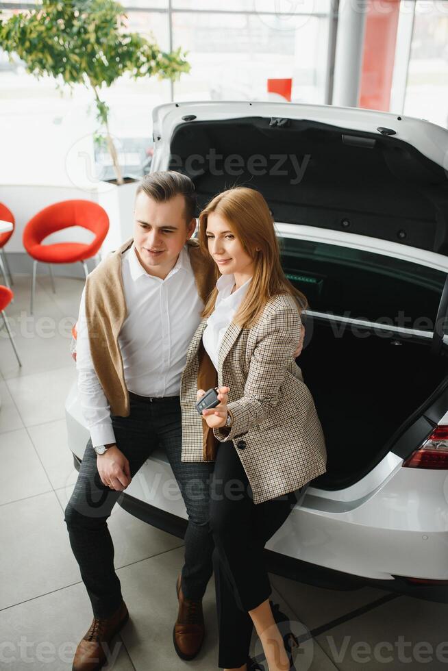 joven hermosa contento Pareja comprando un coche. marido comprando coche para su esposa en un salón. coche compras concepto foto