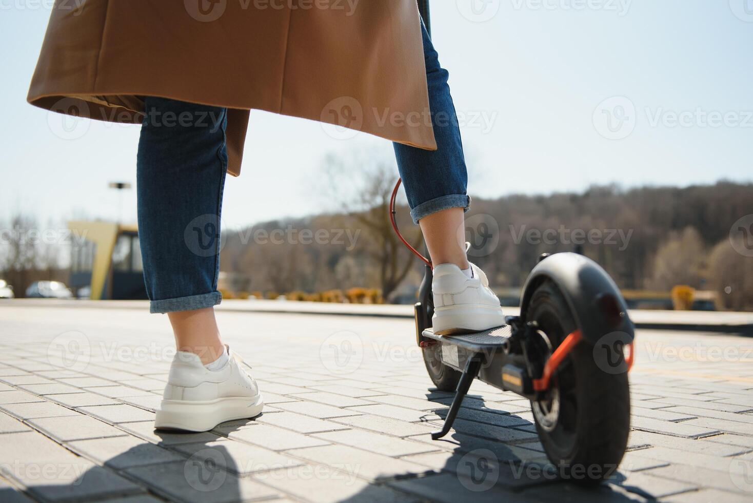Cropped on woman legs feet riding on electric kick scooter in city photo