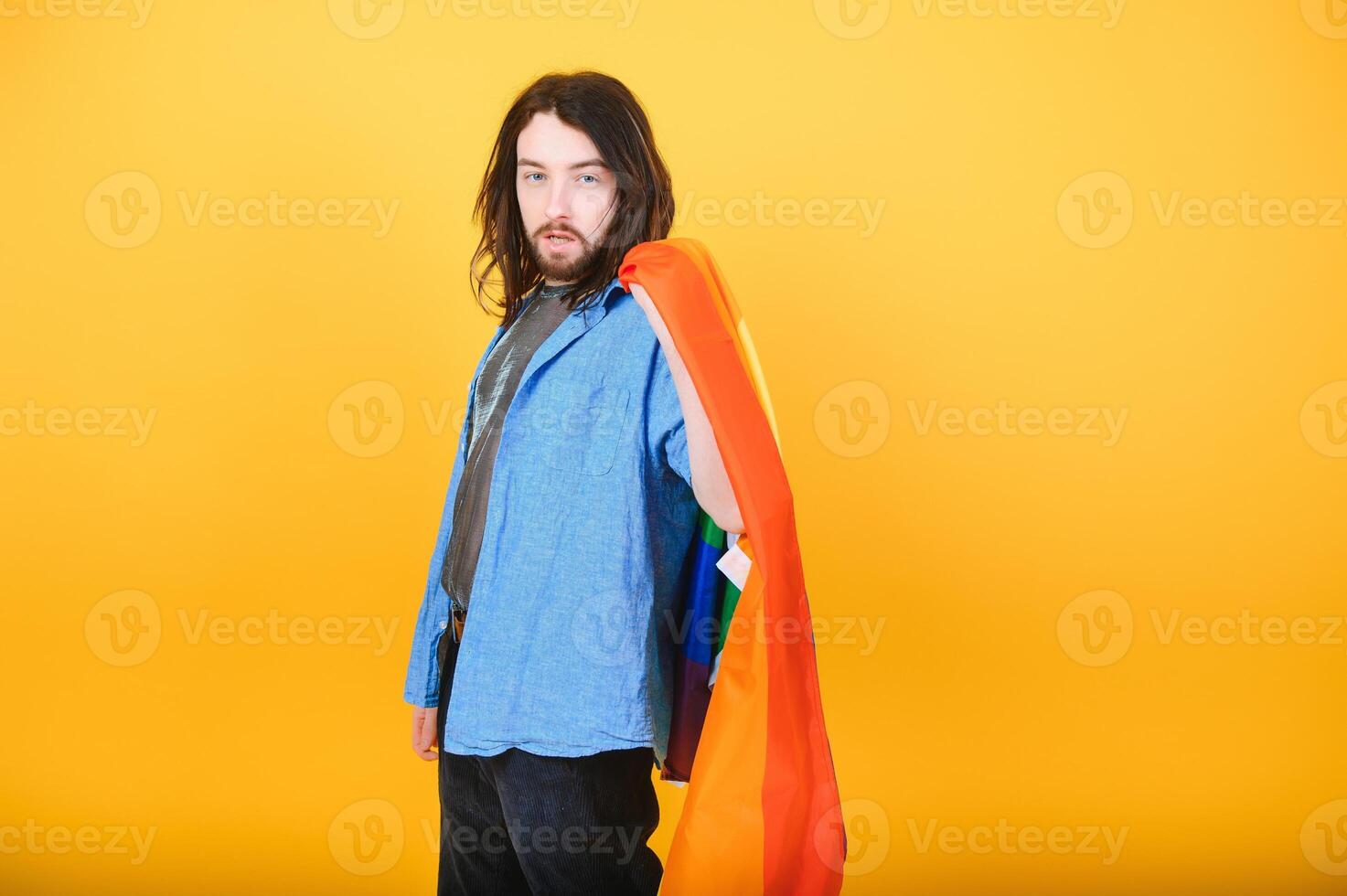 hermoso joven hombre con orgullo movimiento lgbt arco iris bandera en hombro en contra blanco antecedentes. hombre con un gay orgullo bandera. foto