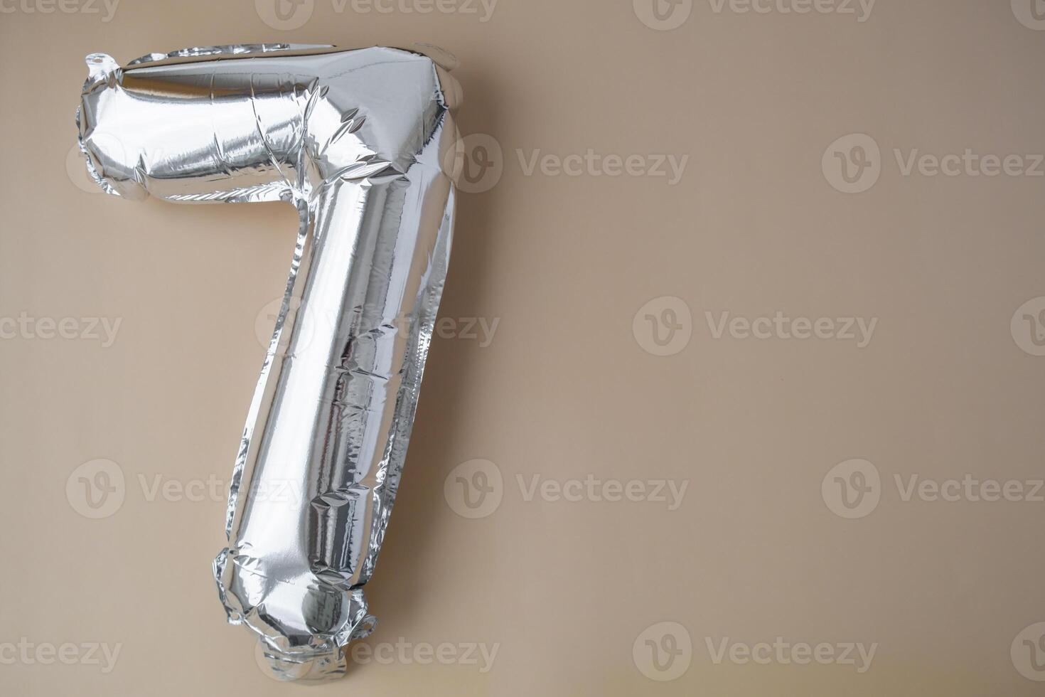 7 seven metallic balloon on beige neutral background. Greeting card silver foil balloon number Happy birthday holiday concept. Copy space for text. Celebration party congratulation decoration photo