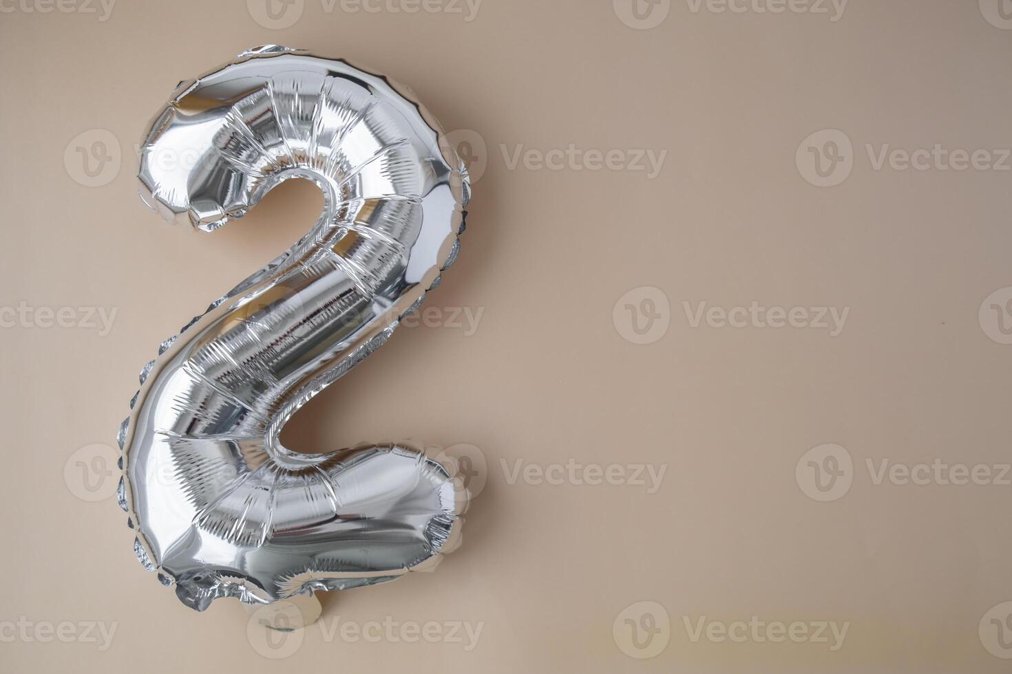 2 two metallic balloon on beige neutral background. Greeting card silver foil balloon number Happy birthday holiday concept. Copy space for text. Celebration party congratulation decoration photo