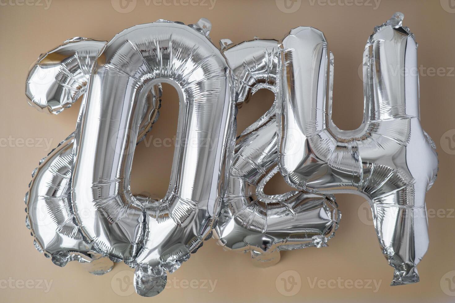 Silver foil number 2024 celebration new year balloon on neutral beige background. Happy New year greetings concept. Two thousand twenty-fourth year Christmas holiday concept photo