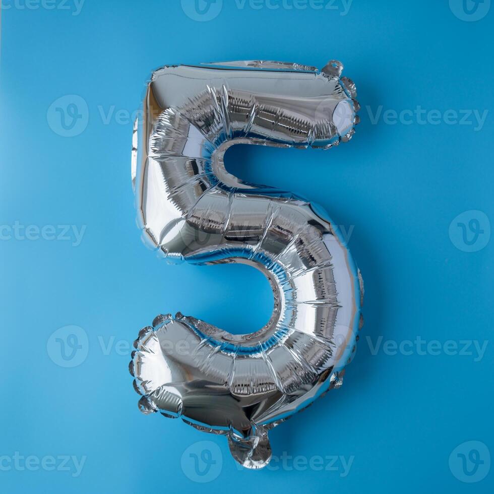 5 five metallic balloon isolated on blue background. Greeting card silver foil balloon number Happy birthday holiday concept. Copy space for text. Celebration party congratulation decoration photo