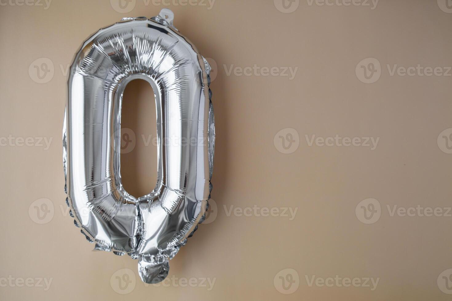 0 ZERO metallic balloon on beige neutral background. Greeting card silver foil balloon number Happy birthday holiday concept. Copy space for text. Celebration party congratulation decoration photo