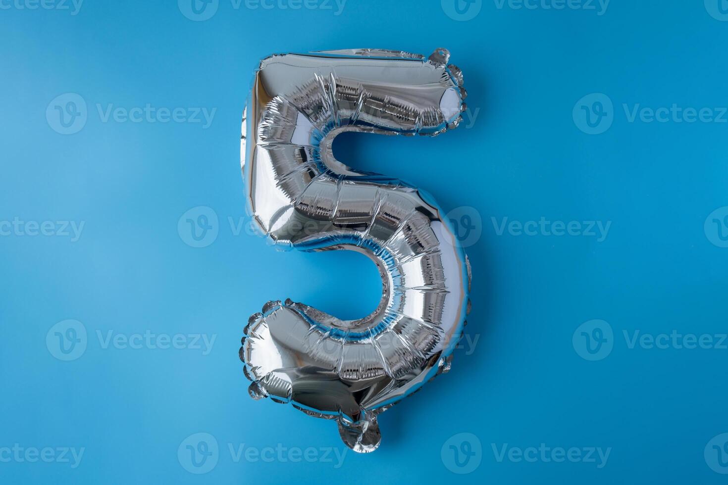 5 five metallic balloon isolated on blue background. Greeting card silver foil balloon number Happy birthday holiday concept. Copy space for text. Celebration party congratulation decoration photo