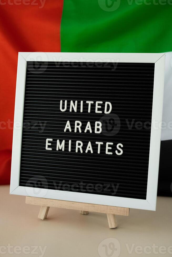Text UNITED ARAB EMIRATES on background waving flag of UAE. National holiday, Independence Commemoration Day Muslim, congratulations. Arabian holidays. Advertisement of Dubai celebration photo