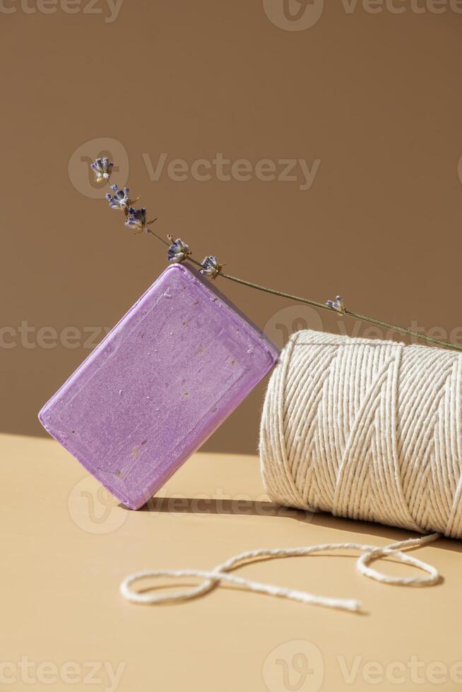 Lavender soap on beige background with spool of white cotton rope copy space for your text. Advertisement template mock up. Skincare homemade natural cosmetic concept. Organic dry lavender flower. Handmade soap photo