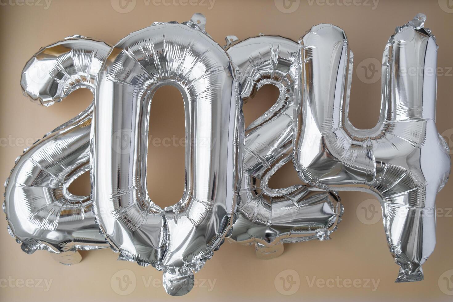 Silver foil number 2024 celebration new year balloon on neutral beige background. Happy New year greetings concept. Two thousand twenty-fourth year Christmas holiday concept photo