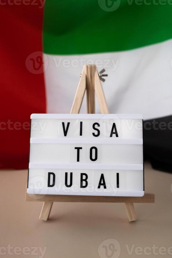 Lightbox with text VISA TO DUBAI on background of waving UAE flag made from silk. United Arab Emirates flag with concept of tourism and traveling. Inviting greeting card, advertisement. Dubai welcoming card photo