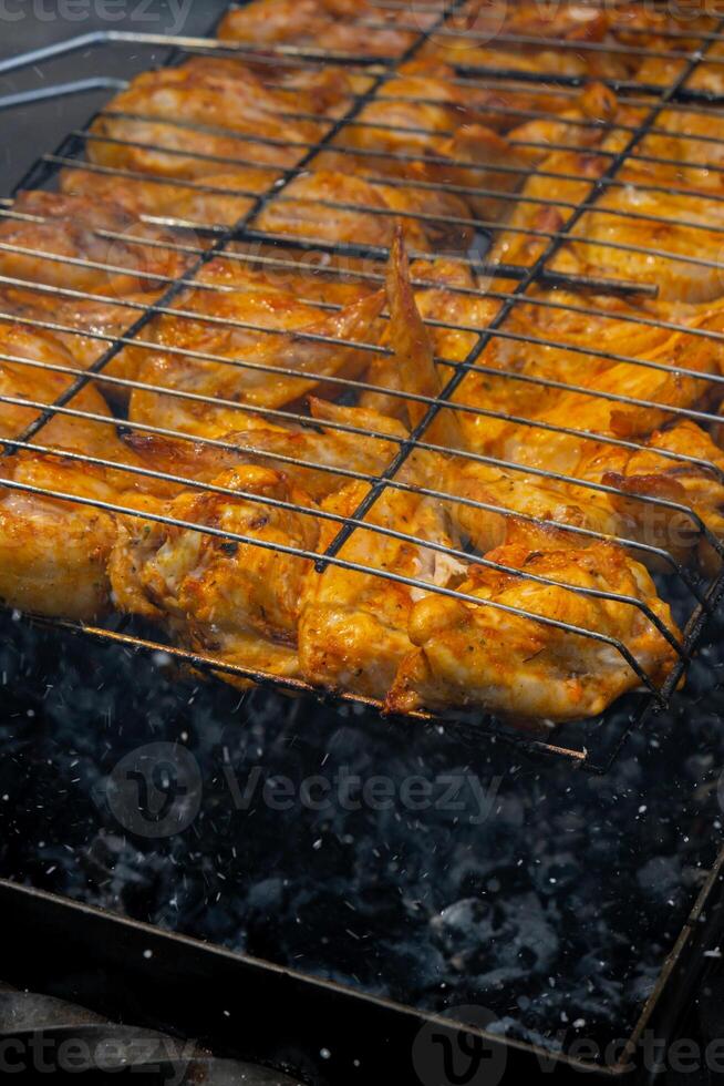 Delicious chicken frying on barbecue grill grate outdoor. Seasoning falling on fresh grilled chicken wings. Summer party food ideas. BBQ Juicy roasting chicken grill legs on grill grate photo