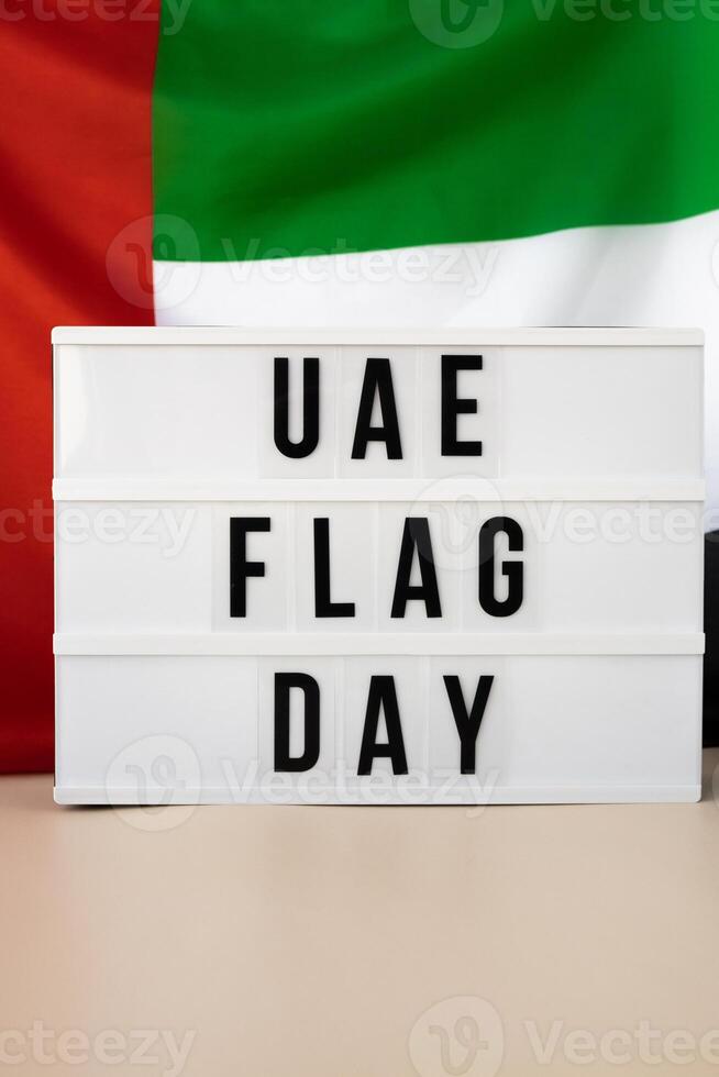 Lightbox with text UAE FLAG DAY on United Arab Emirates waving flag made from silk material. Independence Commemoration Day Muslim Public holiday celebration background. The National Flag of UAE. Patriotism photo