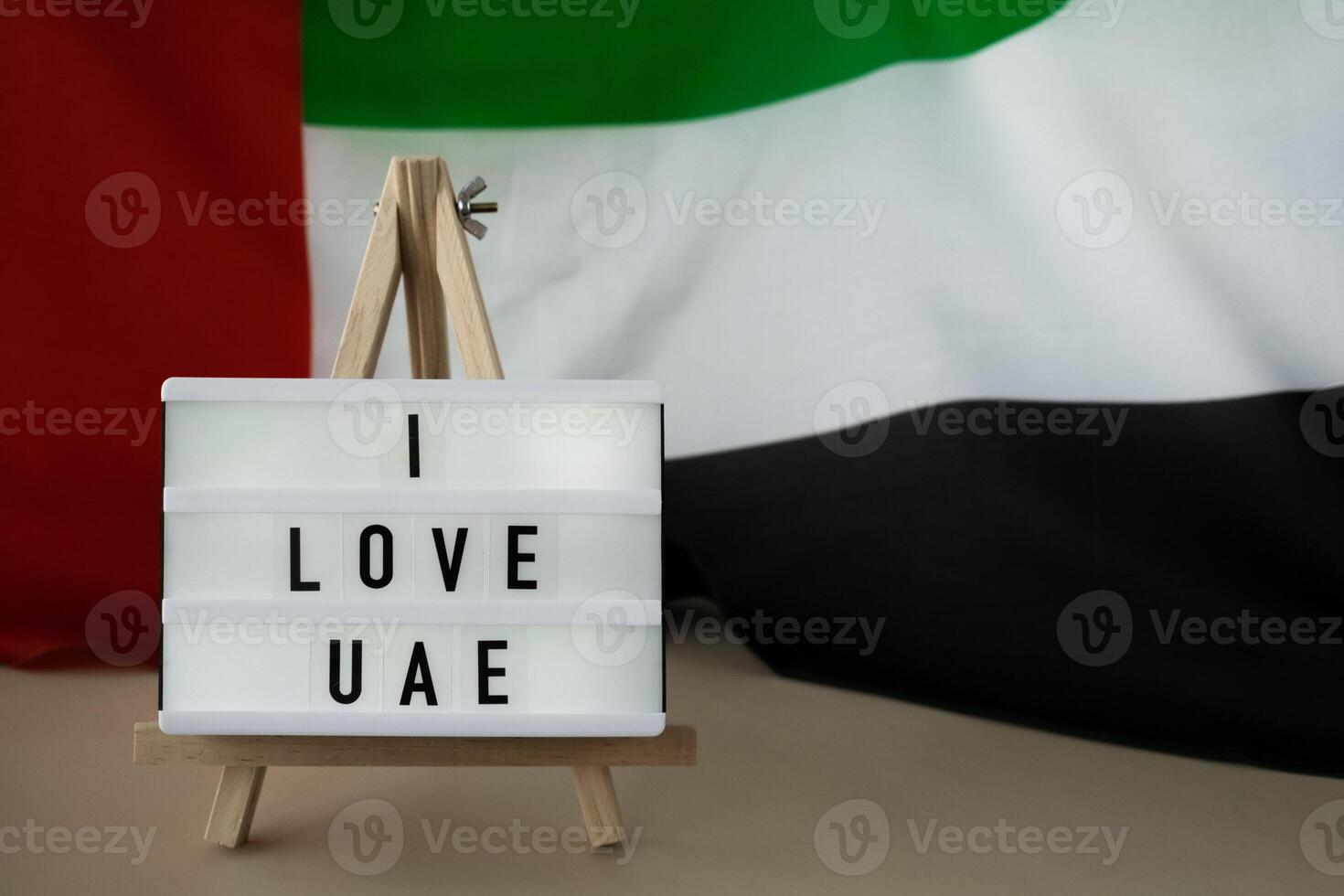 Message text I LOVE UAE on background of waving UAE flag made from silk. United Arab Emirates flag with concept of tourism and traveling. Inviting greeting card, advertisement. Dubai welcoming card photo