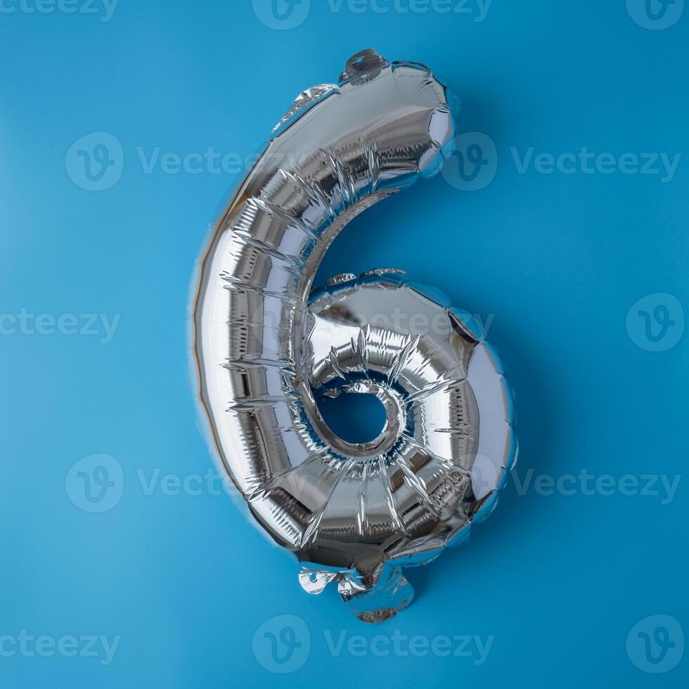 6 six metallic balloon isolated on blue background. Greeting card silver foil balloon number Happy birthday holiday concept. Copy space for text. Celebration party congratulation decoration photo