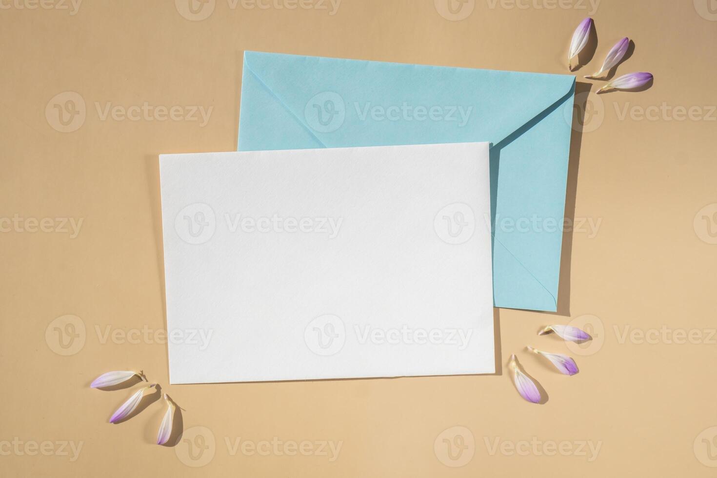 Beautiful little violet flowers on postal blue envelope on beige background, empty paper note copy space for text, spring time, greeting card for holiday. Flower delivery concept photo