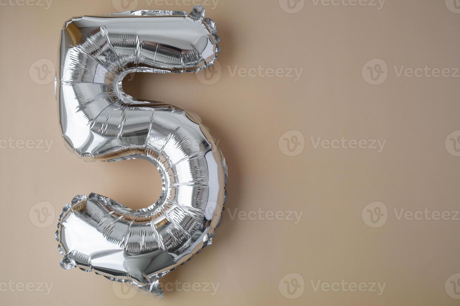 5 five metallic balloon on beige neutral background. Greeting card silver foil balloon number Happy birthday holiday concept. Copy space for text. Celebration party congratulation decoration photo