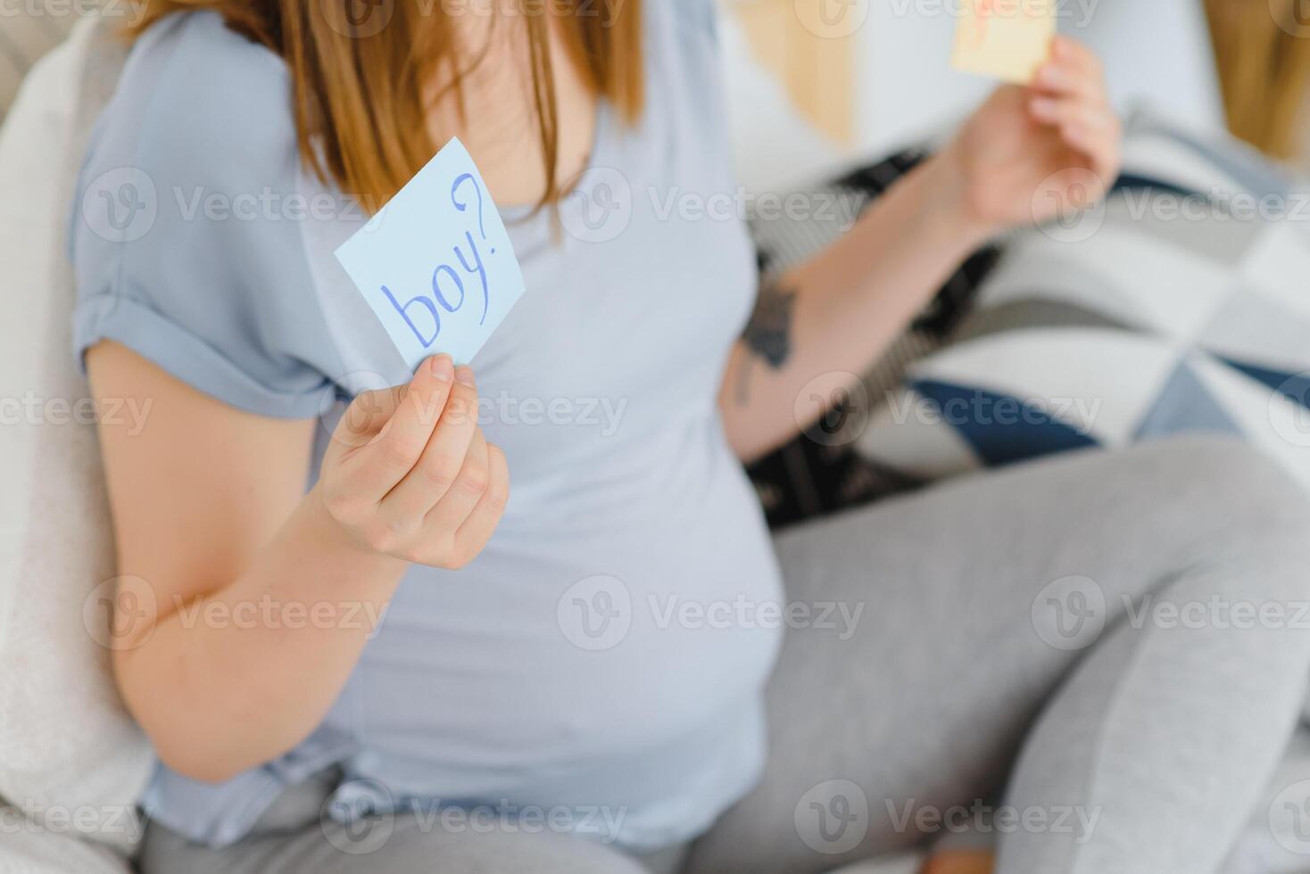 Pregnant woman in bed in the bedroom holding a question card, boy or girl. photo