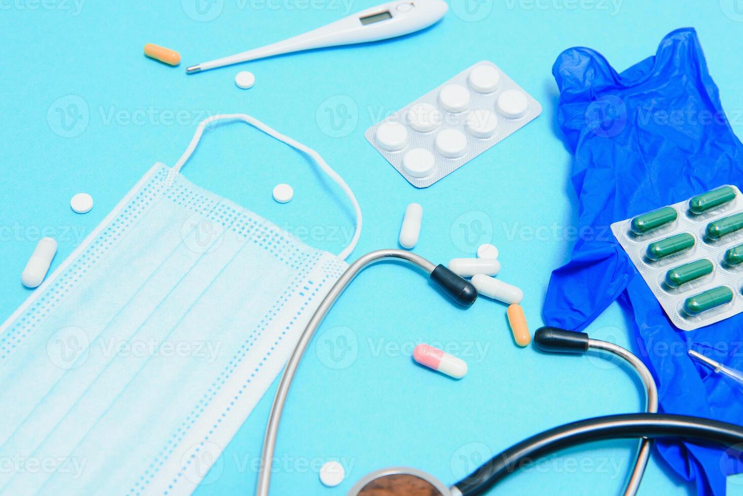 Scattered white pills on blue table.Medical, pharmacy and healthcare concept. Blue background white pills with a medical statoscope, top view photo