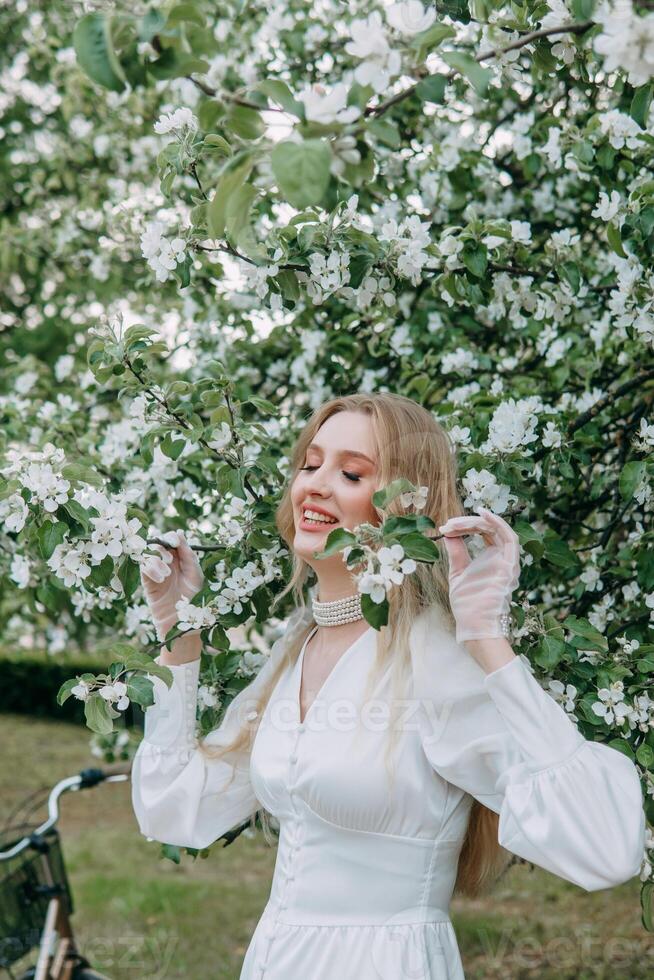 un rubia niña con largo pelo en un caminar en un primavera parque. primavera y floreciente manzana arboles foto