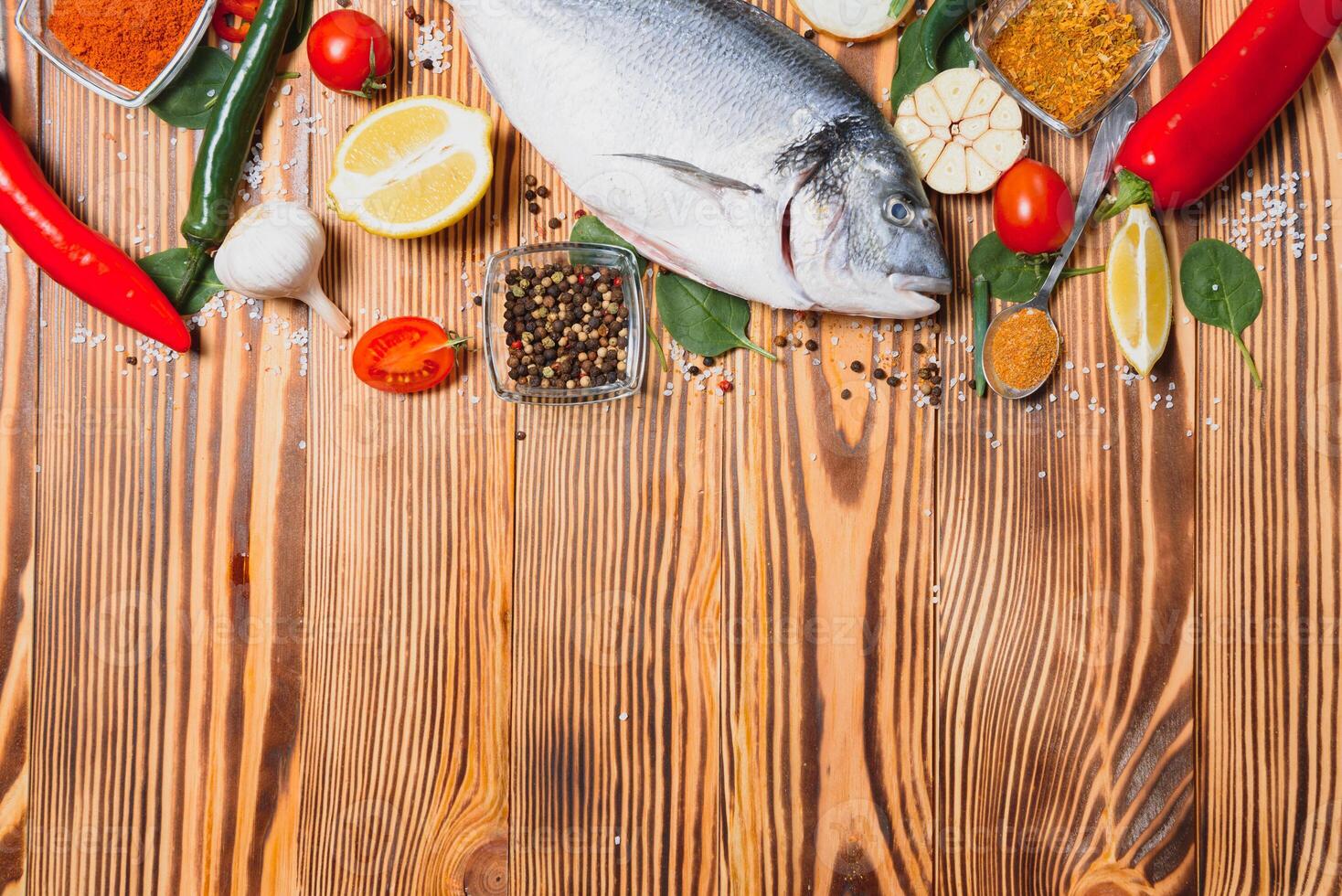 Fresco crudo dorado pescado en horneando papel con limón, pimienta, Tomates y varios especias en de madera antecedentes con Copiar espacio. foto