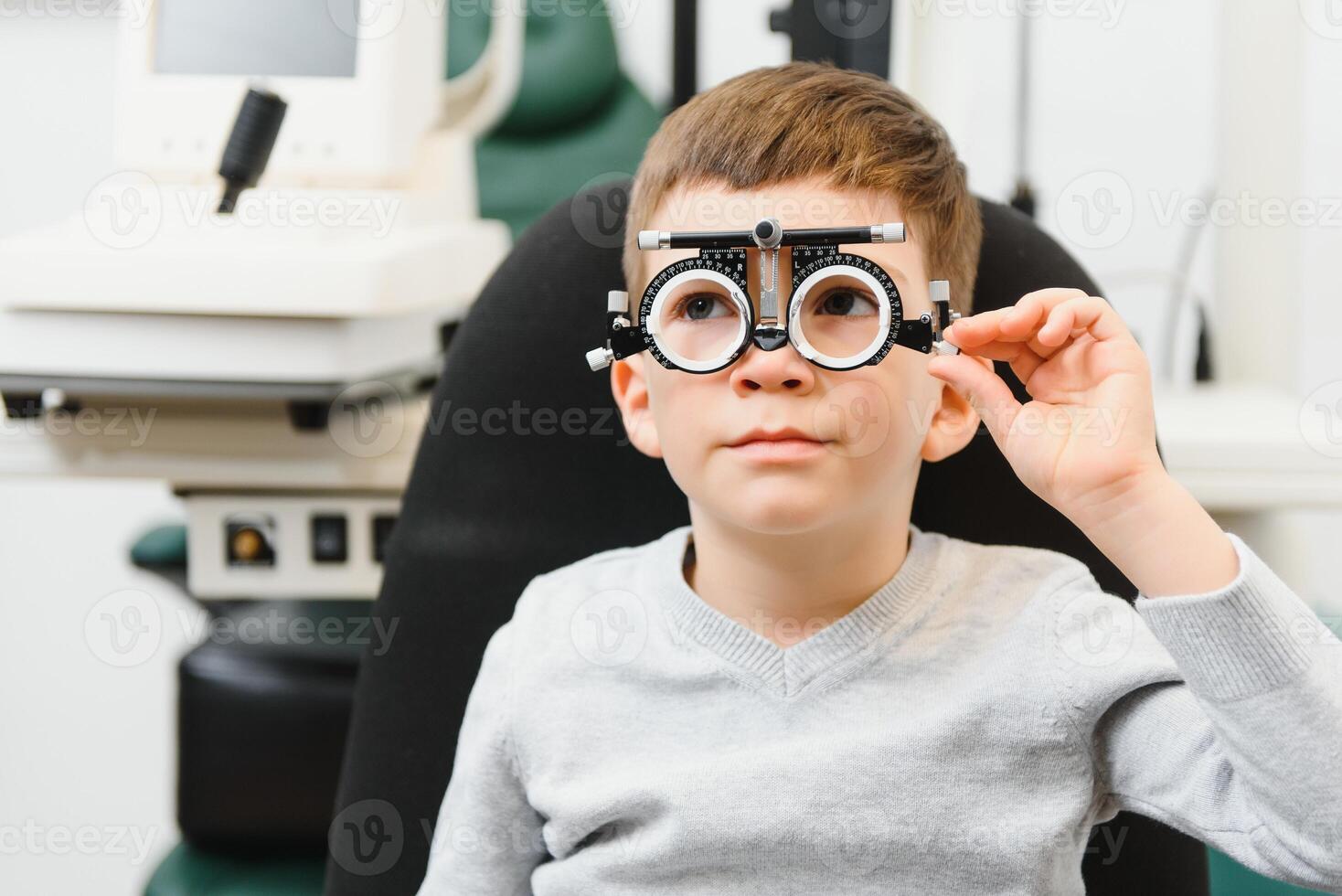 Young boy undergoing eye test with spectacles in medical clinic. photo