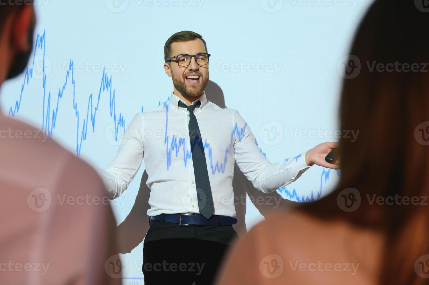 Business Conference Meeting Presentation Businessman does Financial Analysis talks to Group of Businessspeople. Projector Screen Shows Stock Market Data, Investment Strategy, Revenue Growth photo