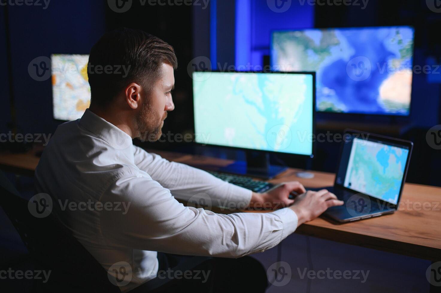Male Data Scientist Works on Personal Computer Control and Monitoring Room. Map Surveillance of People Walking on City Streets photo