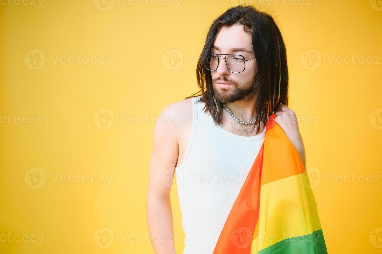 hermoso joven hombre con orgullo movimiento lgbt arco iris bandera en hombro en contra blanco antecedentes. hombre con un gay orgullo bandera. foto