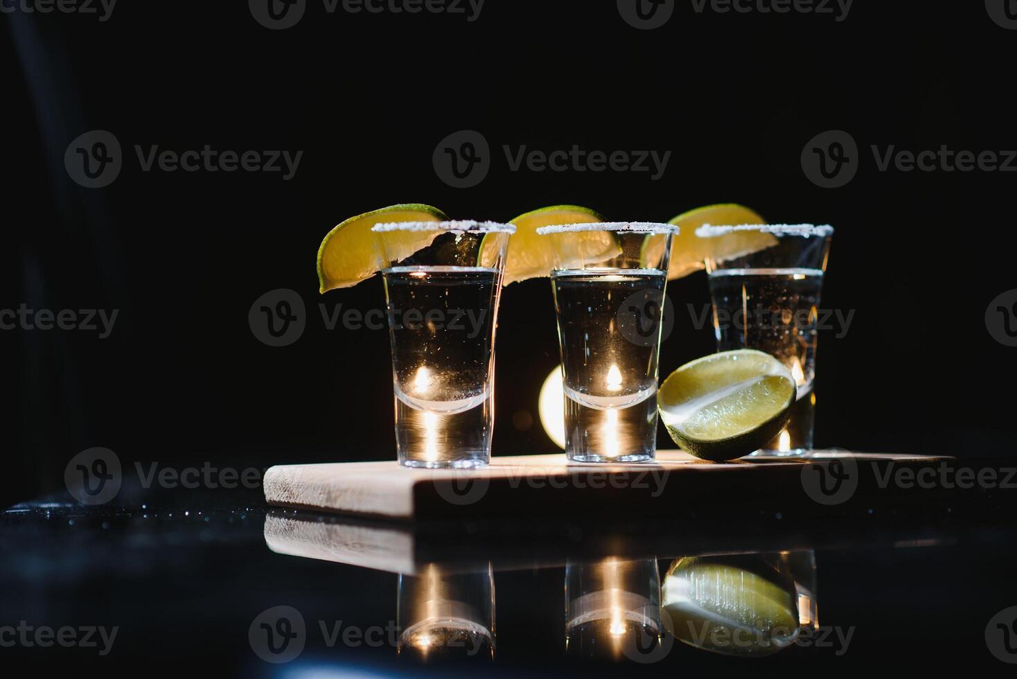 Tasty alcohol drink cocktail tequila with lime and salt on vibrant dark background. Closeup. photo