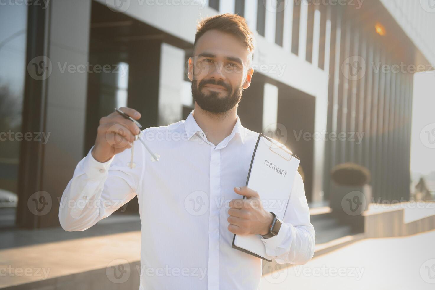 Real estate agent holding key on blurred background, closeup photo