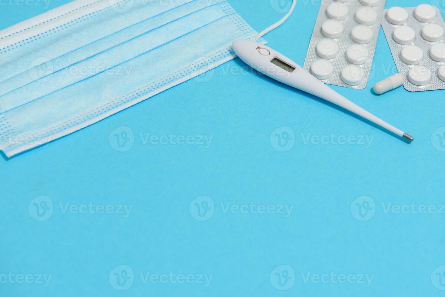 Scattered white pills on blue table.Medical, pharmacy and healthcare concept. Blue background white pills with a medical statoscope, top view photo