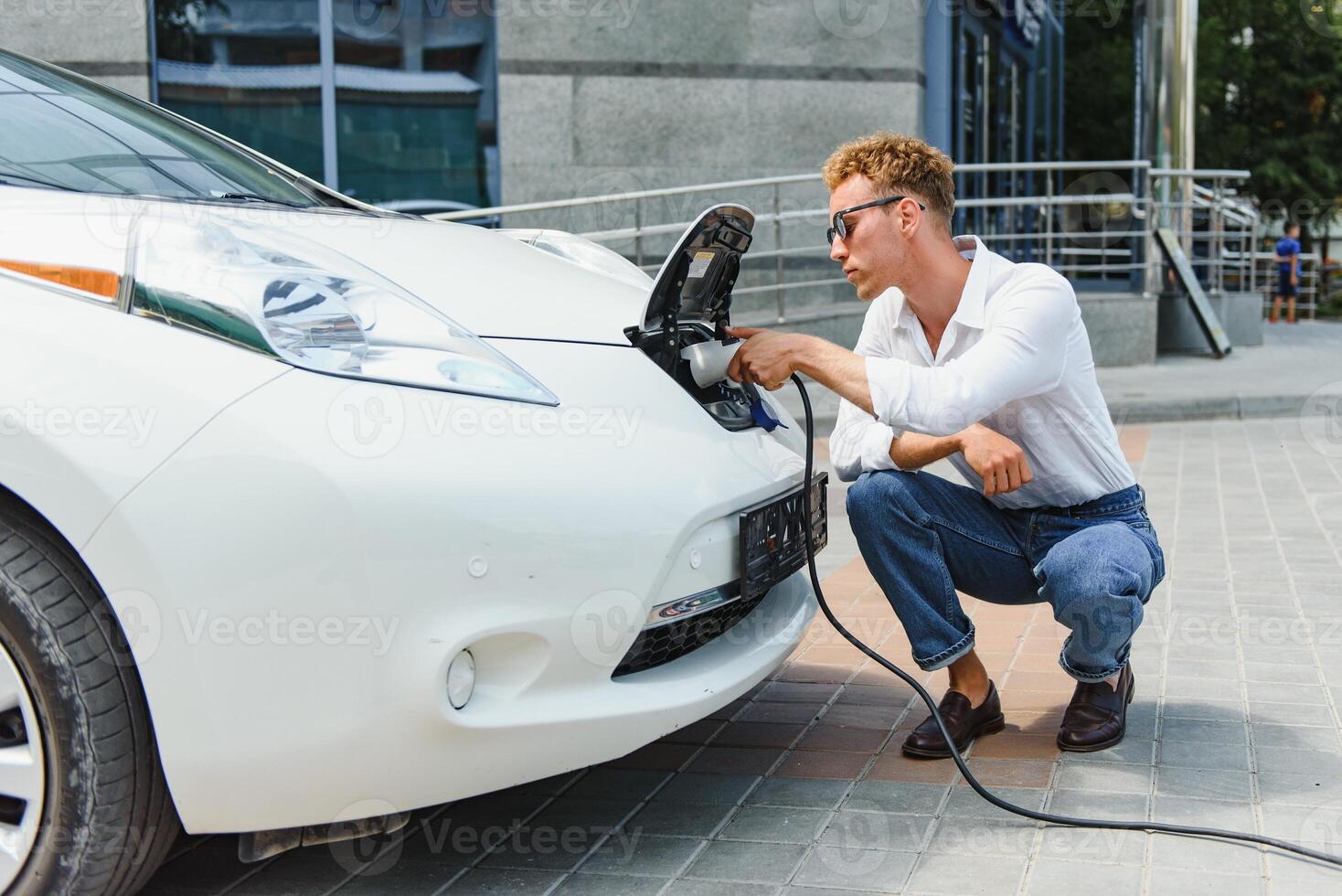 Smiling man unplugging the charger from the car photo