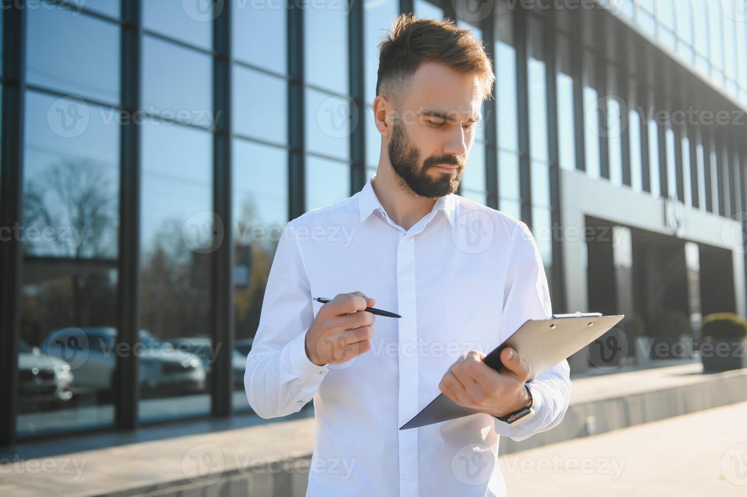 Businessman or real estate agent ready to discuss business and stands against new building photo
