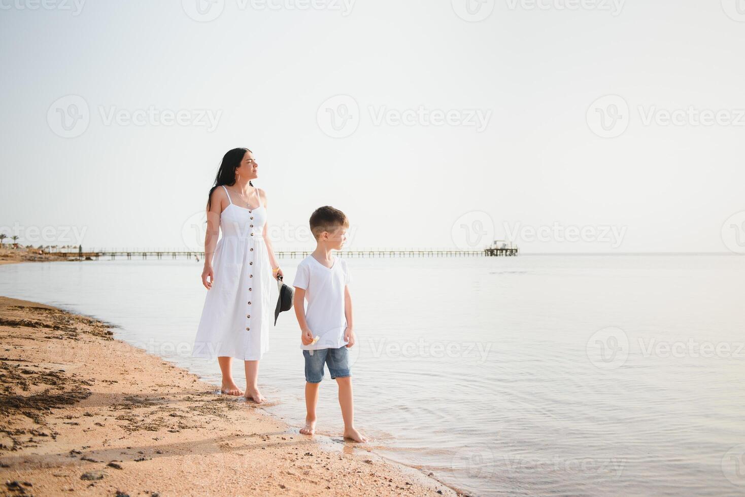 mother and son walking on sunset beach photo