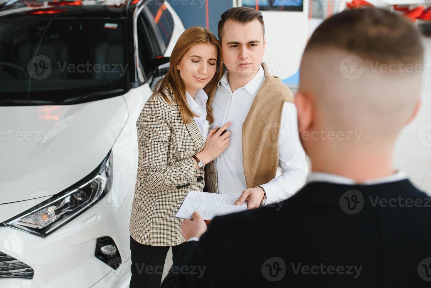 Young couple byuing a car in a car showroom. photo