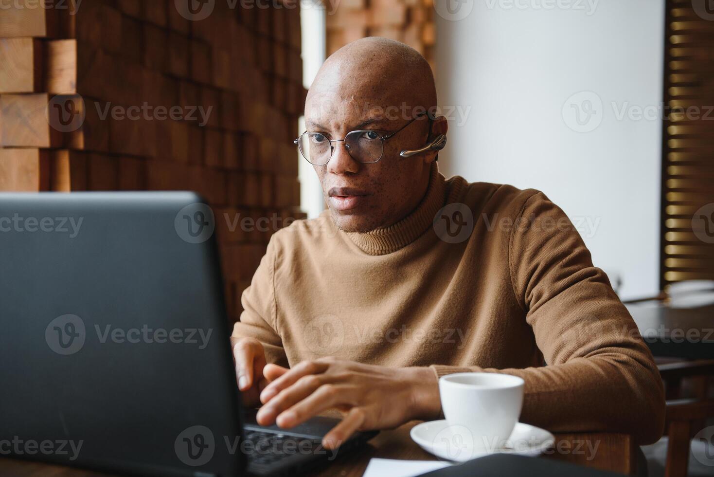 Focused african man wearing headphones watching webinar training making notes study online learning language on computer, black male student looking at laptop elearning in internet write information. photo