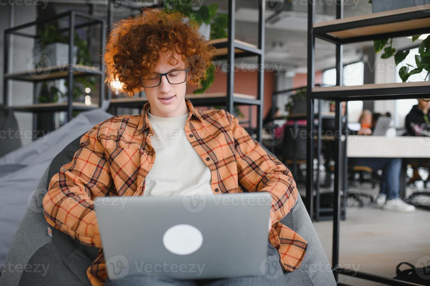 Image of amazing young man sitting in cafe while using laptop computer. photo