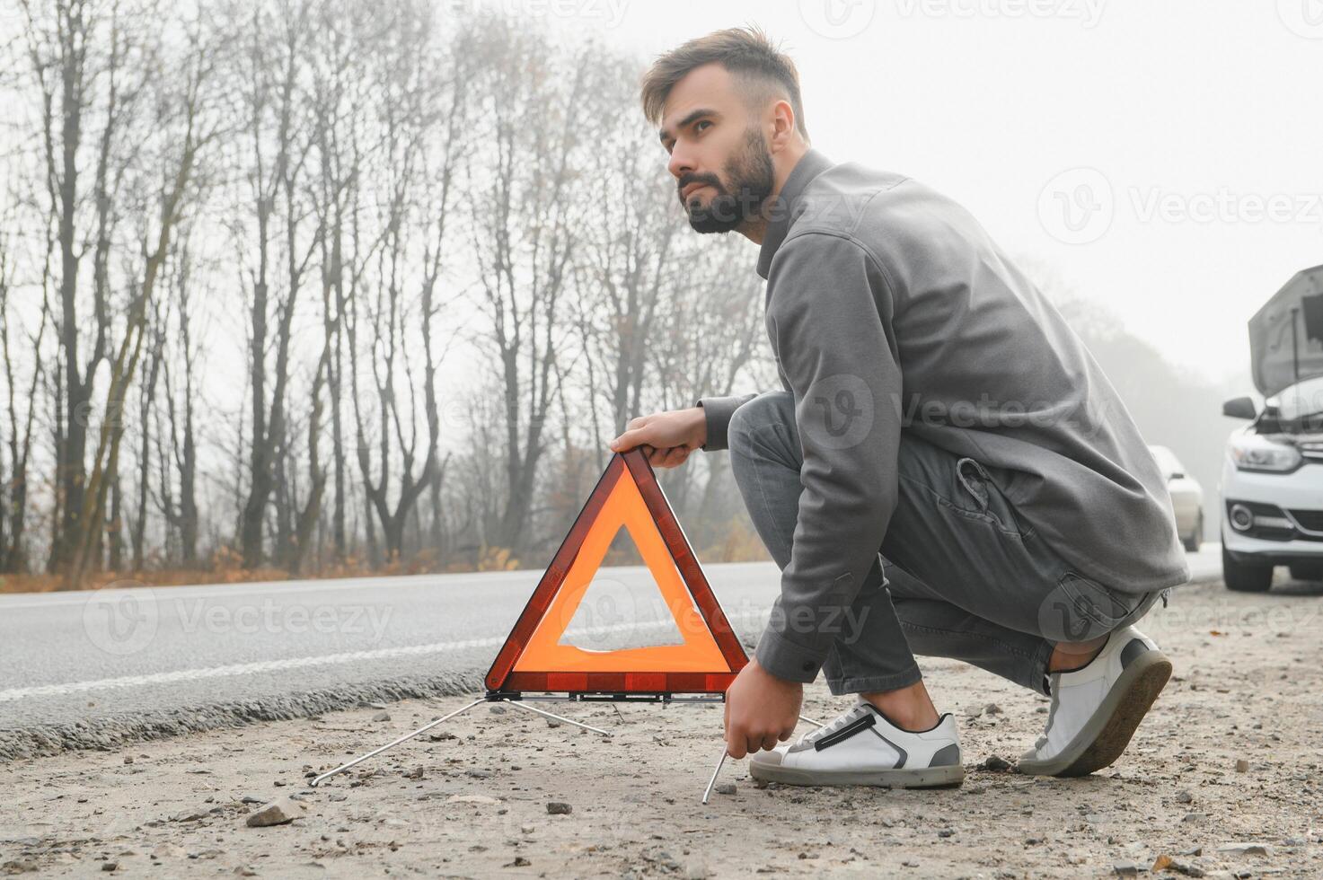 Sad driver having engine problem standing near broken car on the road. Car breakdown concept photo