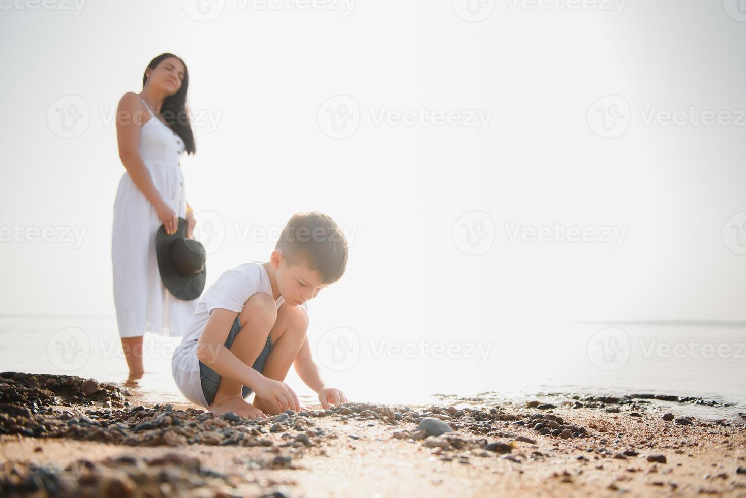 mother and son walking on sunset beach photo