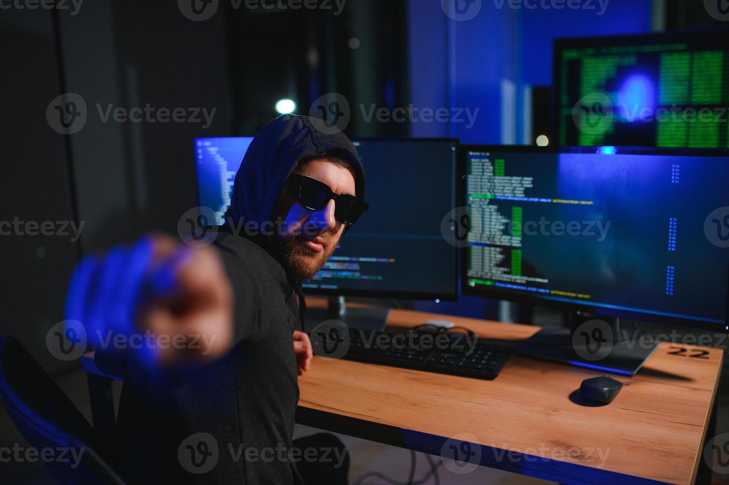 hacker sitting at desk in dark atmosphere. A computer programmer or hacker. Anonymous computer hacker. photo