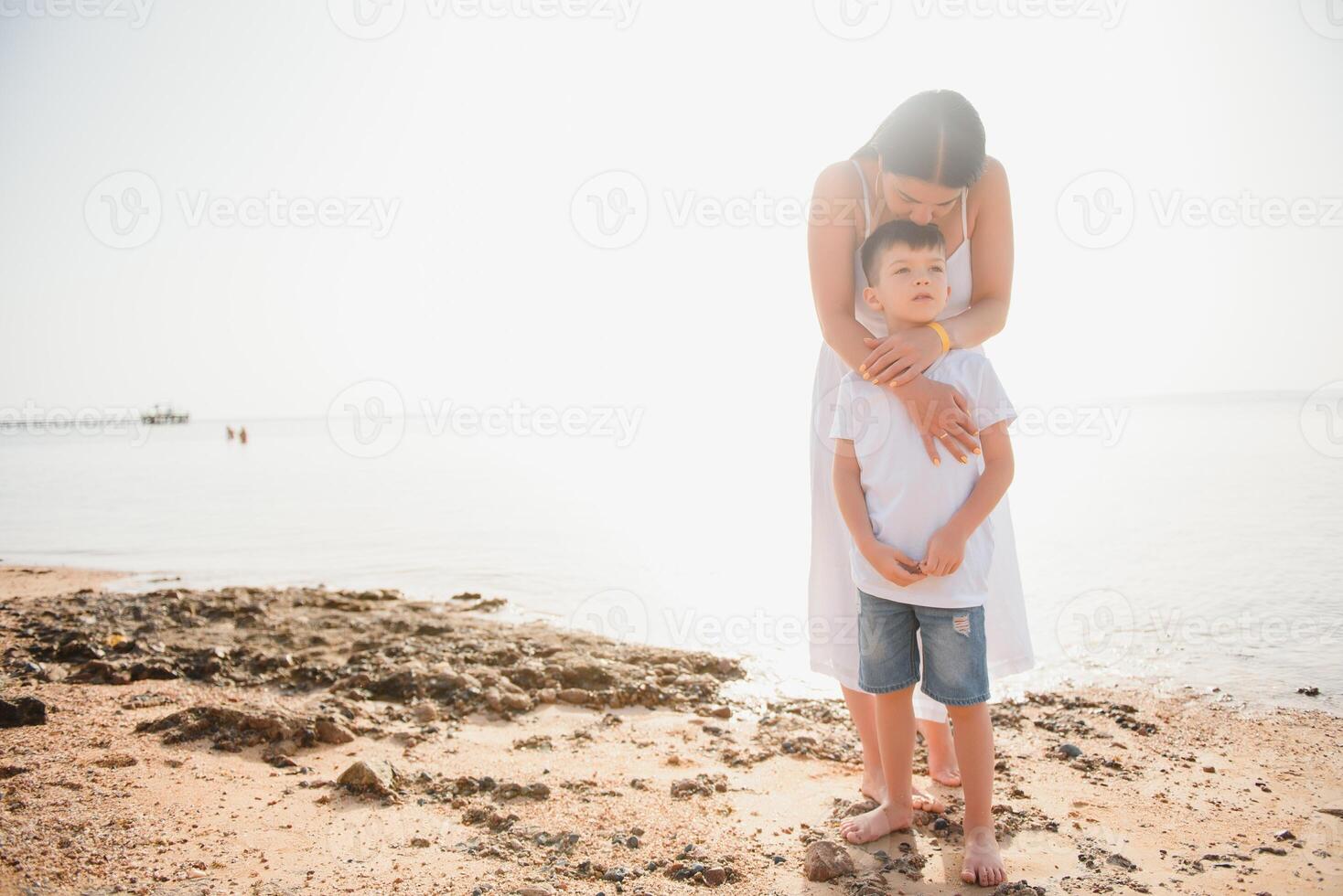 Happy mother and son walk along the ocean beach having great family time on vacation on Pandawa Beach, Bali. Paradise, travel, vacation concept photo