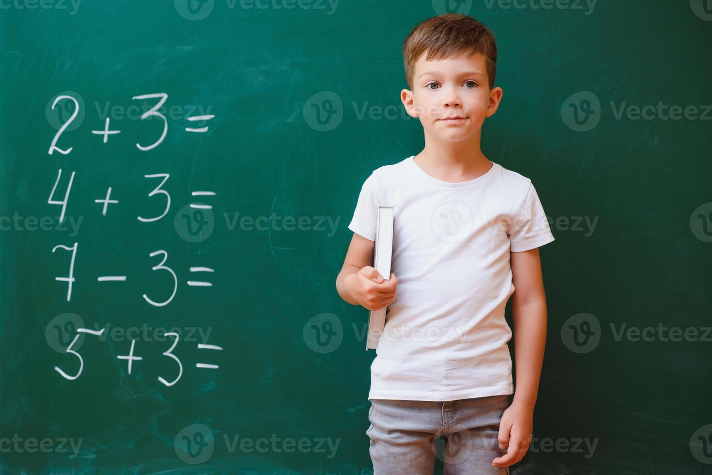 Funny schoolboy near the green school board in the classroom. Elementary school. Back to school. photo