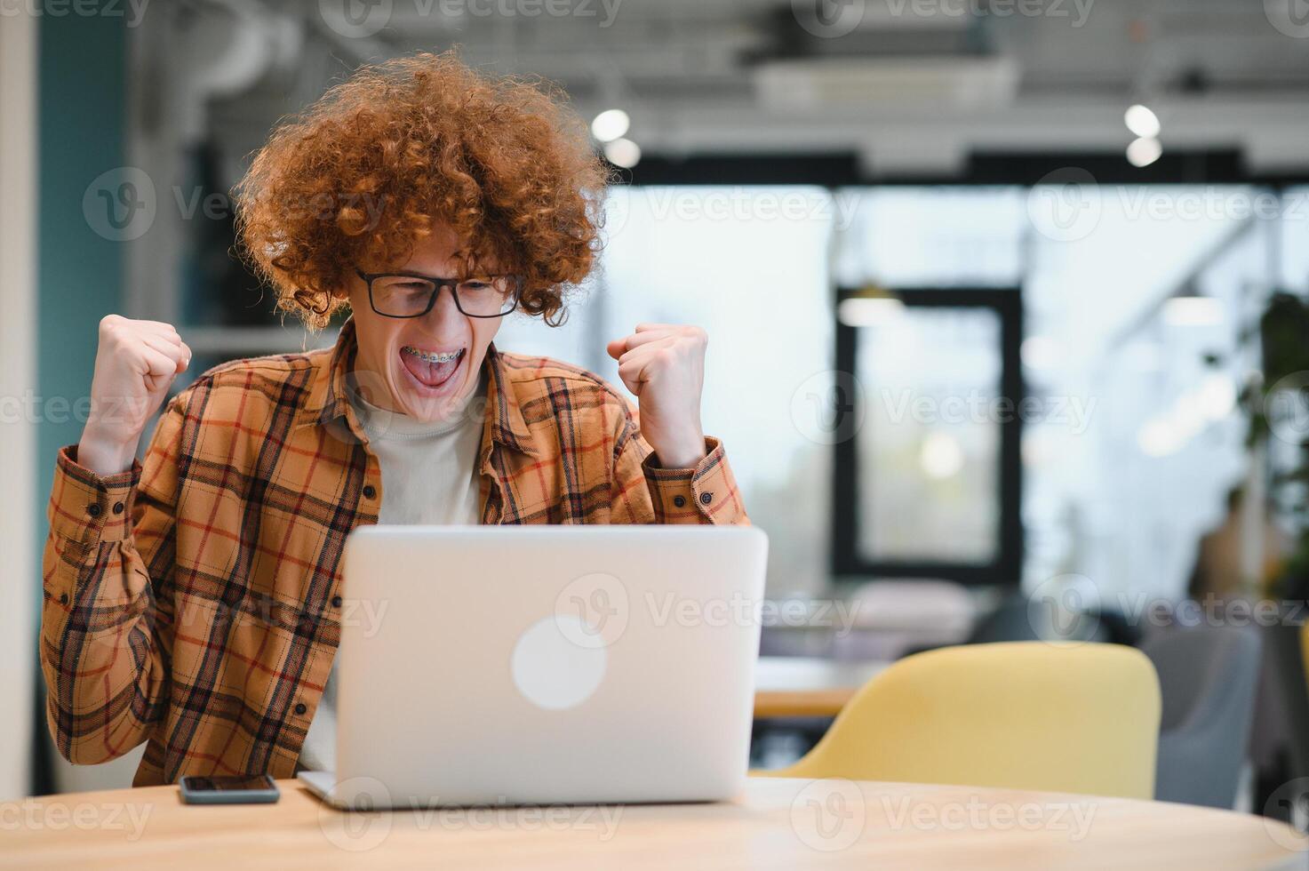 Portrait of Caucasian male freelancer in trendy apparel sitting at cafeteria table and doing remote work for programming design of public website, skilled software developer posing in coworking space. photo