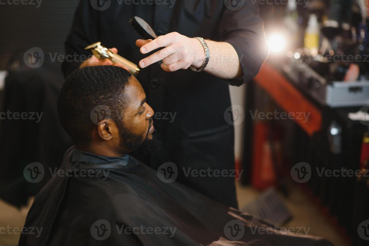 Closeup of process of trimming of hair in barber shop. Qualified barber keeping clipper in hands and correcting shape of hair to male client sitting on chair. Concept of haircut and shaving. photo