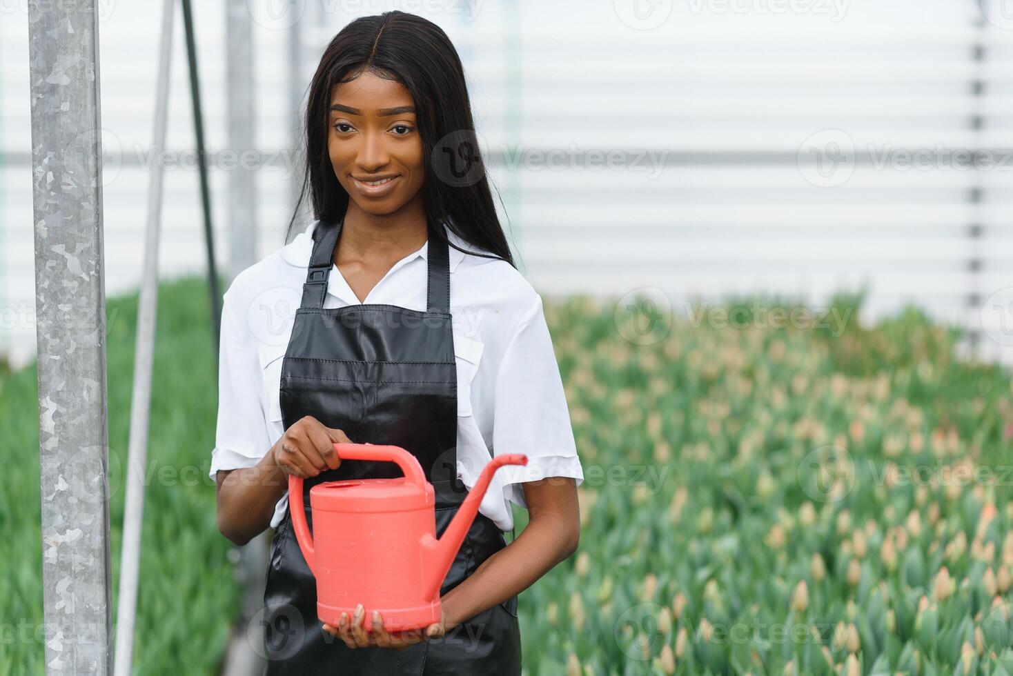 Agriculture management. Smiling african american girl makes photo of flowers plantation in greenhouse, side view, free space