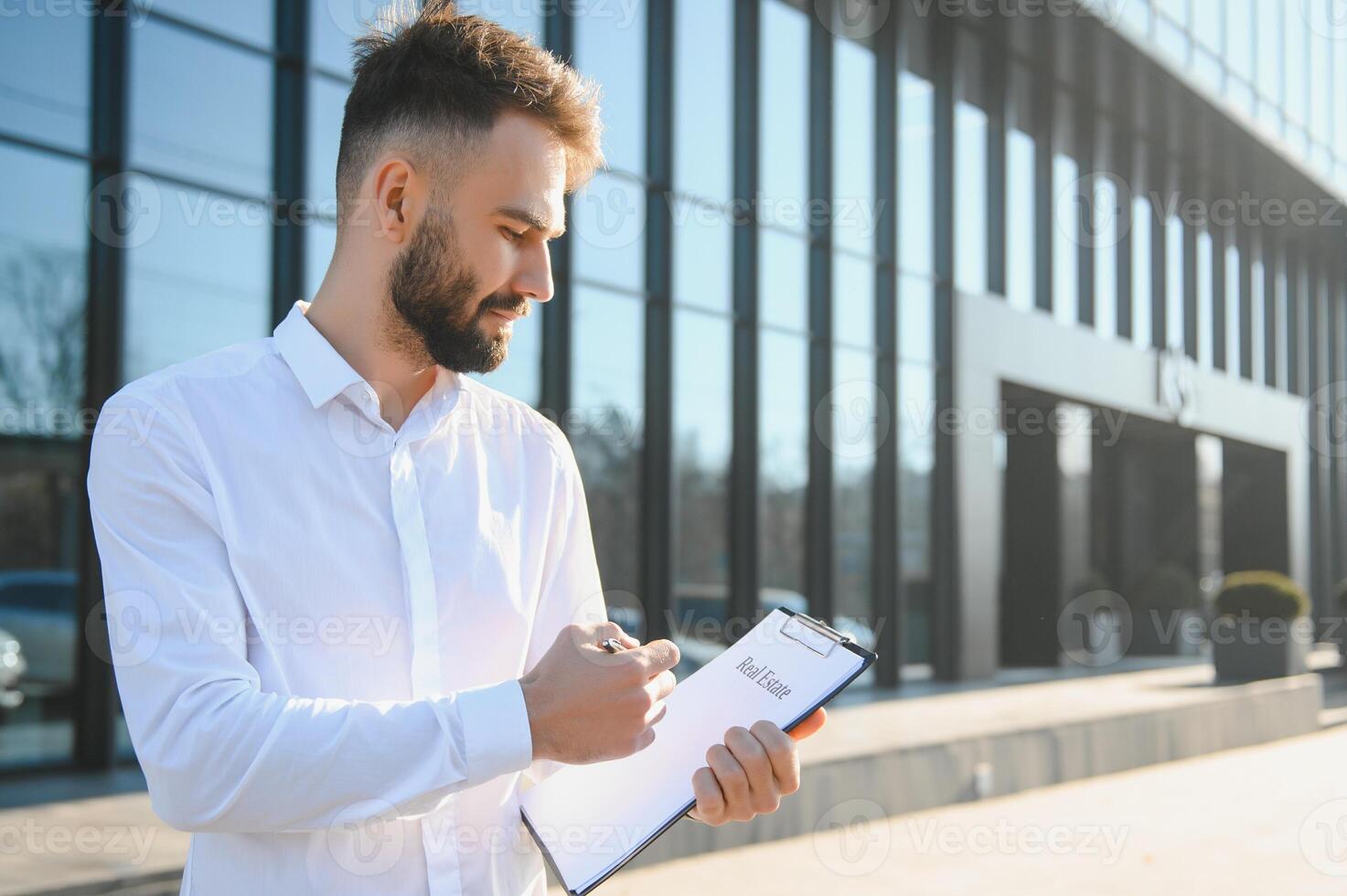 Businessman or real estate agent ready to discuss business and stands against new building photo
