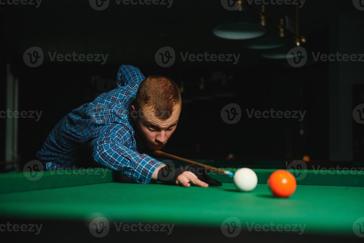 Young handsome man leaning over the table while playing snooker photo