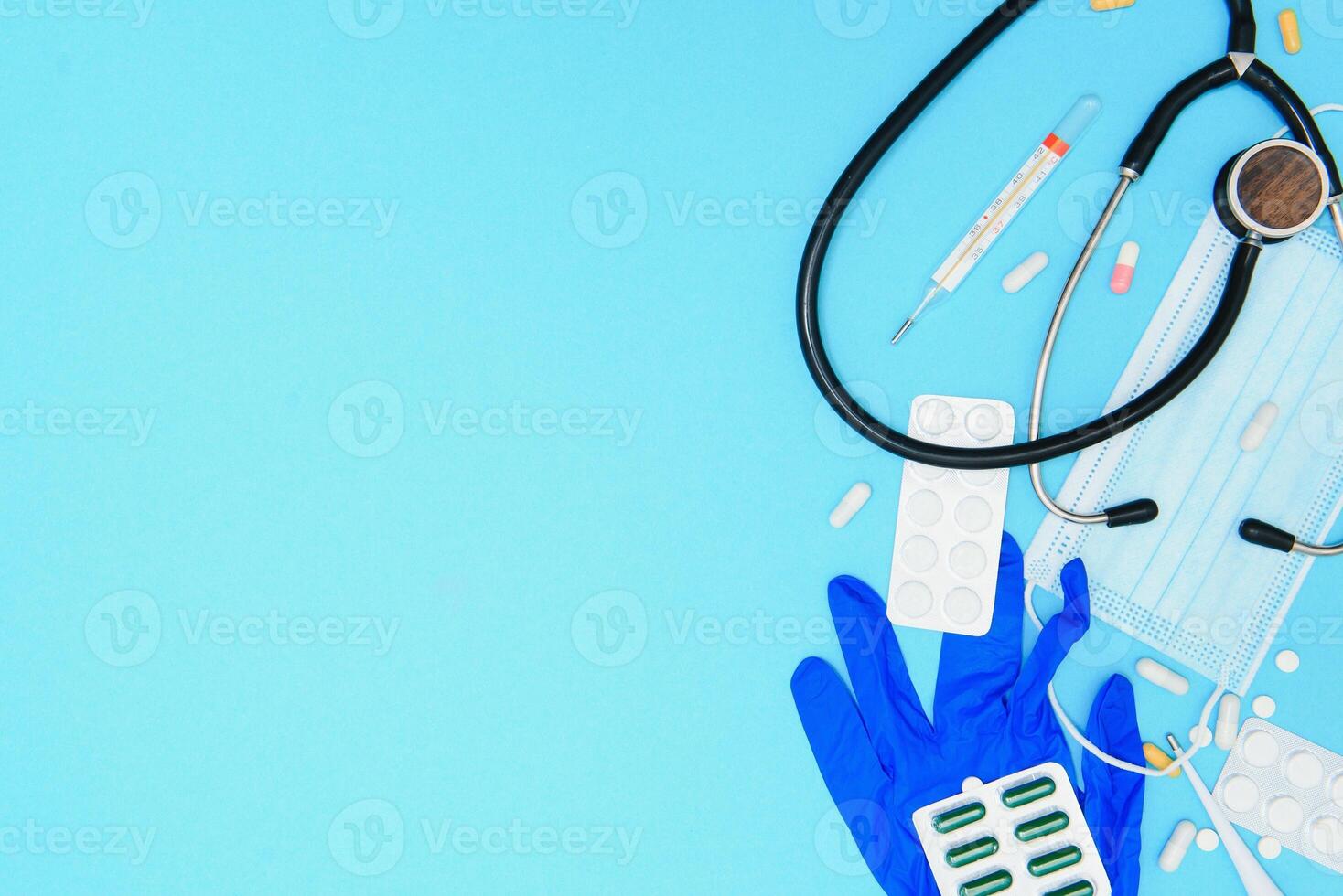Top view of medicines, work tools and accessories doctor, nurse. Medical set - Tablets, thermometer, syringe, ampoules, adhesive plaster and statoscope on a blue background. Flat lay. photo